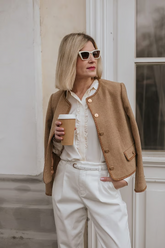 a lady wears a camel jacket with white shirt and pants